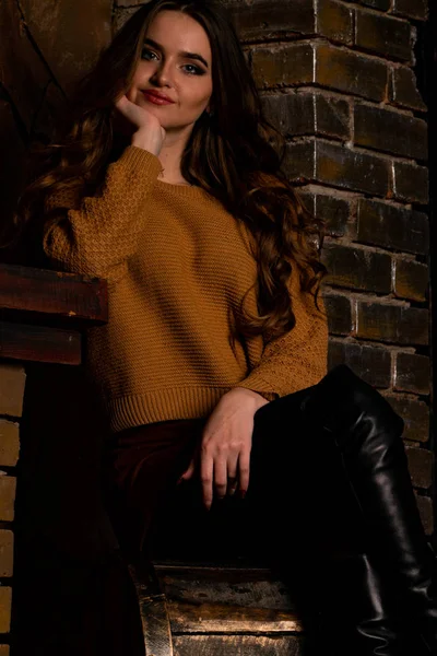 スタジオの暖炉の近くの椅子に座っている魅力的な若い女性 — ストック写真