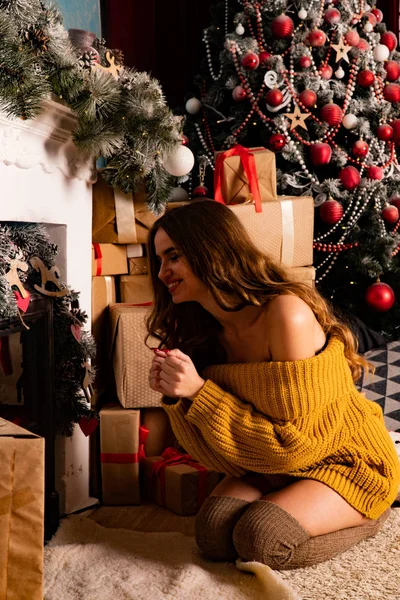 Noel süslemeli stüdyoda şöminenin yanında poz veren güzel esmer genç bir kadın. 