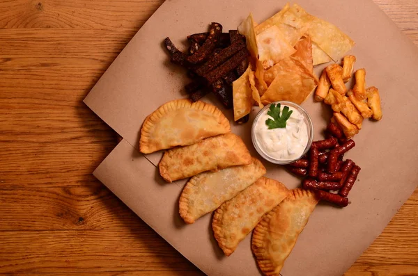 Tortilla chips gegarneerd met gemalen rundvlees, gesmolten kaas, paprika 's en koriander bladeren in plaat op houten tafel — Stockfoto