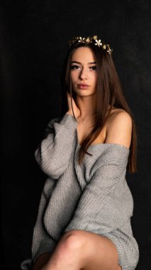 Stüdyoda siyah bir arka planda duran kolları olan güzel gri elbiseli seksi bir genç. 
