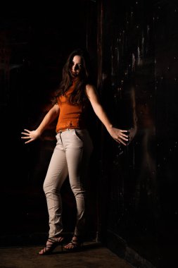 Güzel esmer model, karanlık odada poz veriyor. 