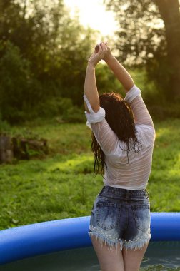Gün batımında, havuzda ıslak güzel bir kız bedeni.