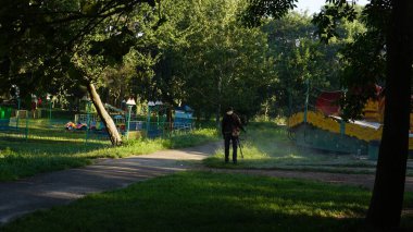 Sabahları parktaki çimleri biçen adam manzarası