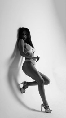 Beyaz iç çamaşırlı ve yüksek topuklu bir kız beyaz arka planda poz veriyor.. 