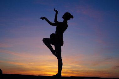 Dans eden dansçı gün batımına karşı havada yarılır.