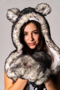 Güzel esmer manken şık kıyafetler içinde, aydınlık odada poz veriyor. 