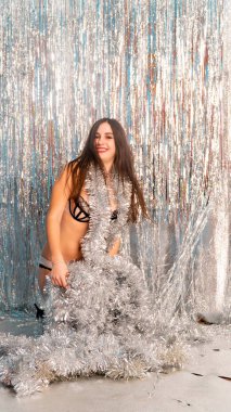 Stüdyoda poz veren parlak noel süsleriyle güzel seksi kadın, tatil konsepti.   