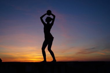 Dans eden dansçı gün batımına karşı havada yarılır.