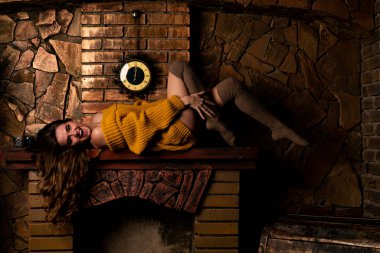 Şöminenin yanında oturan güzel kız. Noel için içi köknar dalları ve oyuncaklarla süslenmiş lüks bir iç mekan.