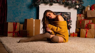 Noel süslemeli stüdyoda şöminenin yanında poz veren güzel esmer genç bir kadın. 