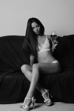 İç çamaşırlarıyla kanepede poz veren sevimli, çekici, çekici bir kızın portresi. 