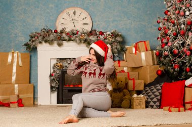 Noel süslemeli stüdyoda şöminenin yanında poz veren çekici esmer kadın.  