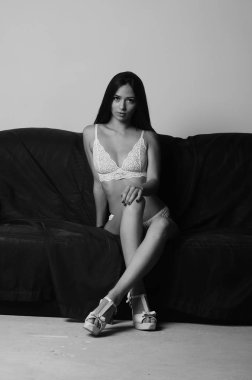 İç çamaşırlarıyla kanepede poz veren sevimli, çekici, çekici bir kızın portresi. 