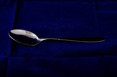 Tekstil arka planında gümüş metal kaşık 