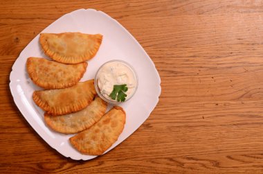 Özbek Doğu Tatar mutfağı, et ve suluguni ile cheburek peynirli sebze ve Yeşiller ahşap bir masa üzerinde beyaz bir tabak içinde.