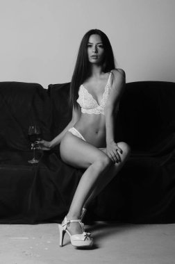 İç çamaşırlarıyla kanepede poz veren sevimli, çekici, çekici bir kızın portresi. 