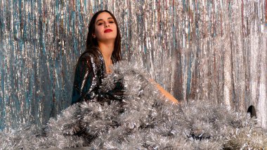 Stüdyoda poz veren parlak noel süsleriyle güzel seksi kadın, tatil konsepti.   