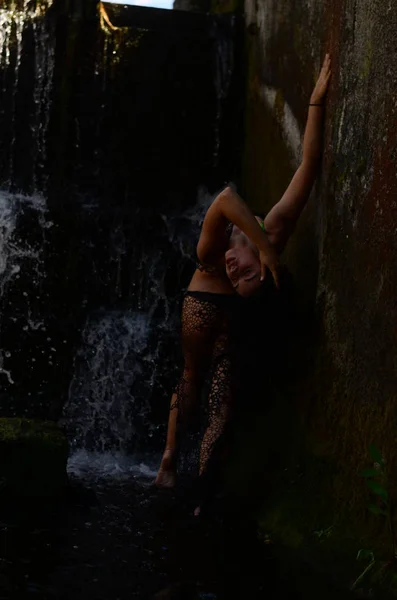 Молодая брюнетка позирует против водопада — стоковое фото
