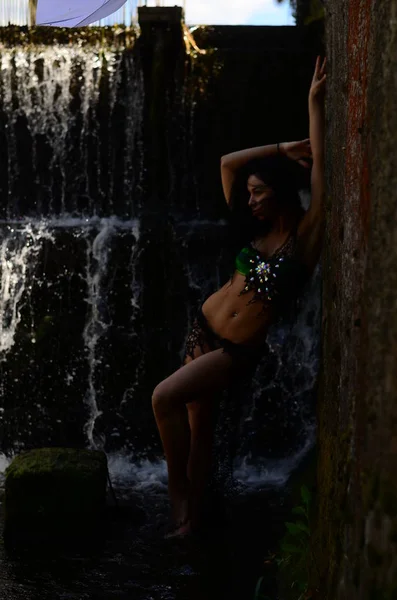 Jeune modèle brune posant contre une cascade — Photo