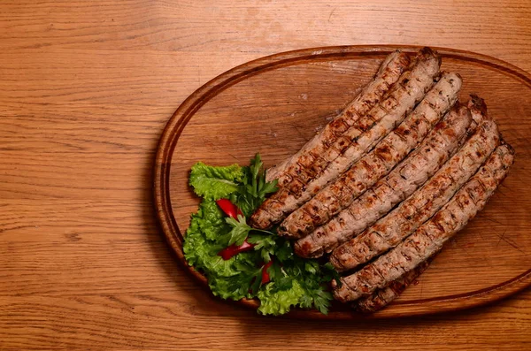 Sabrosas salchichas a la parrilla sobre tabla de madera — Foto de Stock