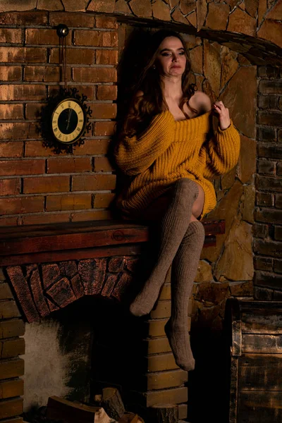 坐在壁炉旁边的漂亮姑娘。用冷杉树枝和玩具装饰奢华的圣诞室内装饰 — 图库照片