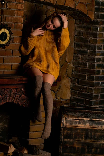 Belle fille assise à côté de la cheminée. Intérieur de luxe décoré pour Noël avec branches de sapin et jouets — Photo