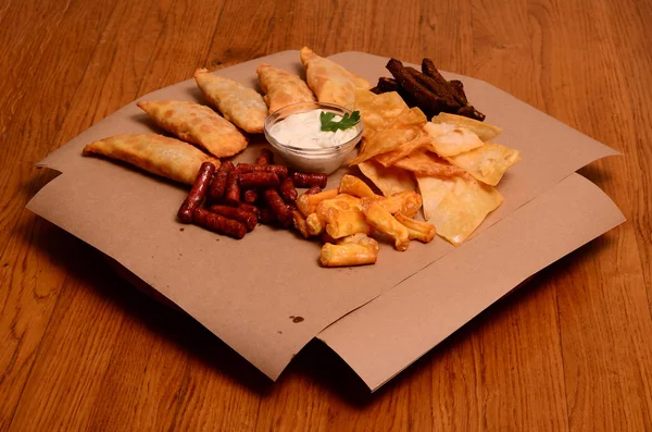 Tortilla chips garnished with ground beef, melted cheese, peppers and cilantro leaves in plate on wooden table — Stock Photo, Image