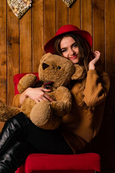 beautiful brunette woman with toy bear posing in wooden studio