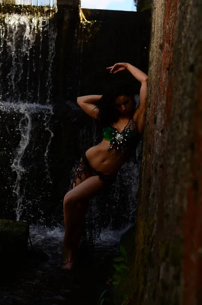 Jonge brunette model poseren tegen een waterval — Stockfoto