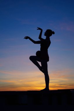 Dans eden dansçı gün batımına karşı havada yarılır.