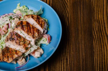 Sosisle kızarmış patatesi karıştırın ve ahşap arka planda salata.