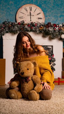 Noel süslemeli stüdyoda şöminenin yanında poz veren güzel esmer genç bir kadın. 