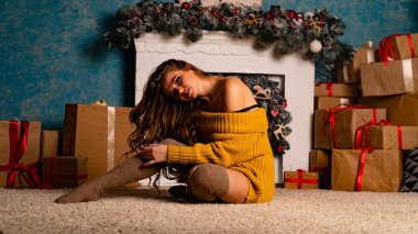 Noel süslemeli stüdyoda şöminenin yanında poz veren güzel esmer genç bir kadın. 