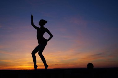 Dans eden dansçı gün batımına karşı havada yarılır.