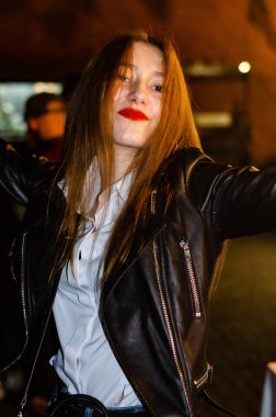 young woman in a leather jacket posing on street
