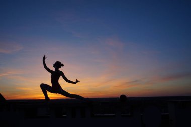 Dans eden dansçı gün batımına karşı havada yarılır.