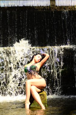 Genç esmer model bir şelale karşı poz