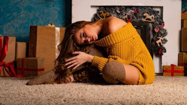 Noel süslemeli stüdyoda şöminenin yanında poz veren güzel esmer genç bir kadın. 