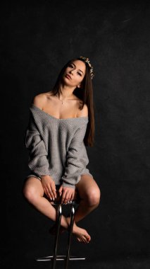 Güzel seksi kız, kısa gri bir elbise, siyah arka plan koltuğu