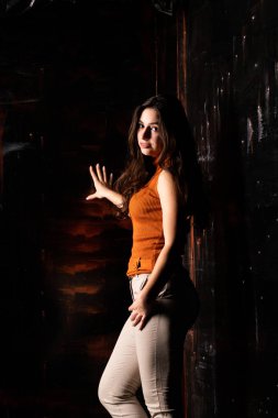 Güzel esmer model, karanlık odada poz veriyor. 