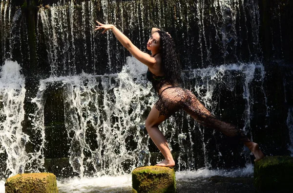 Joven modelo morena posando contra una cascada — Foto de Stock