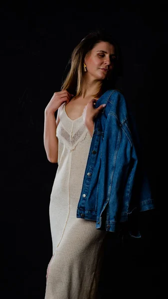 Young beautiful woman wearing in a black leather jacket, black top, short skirt and boots posing over black background. Studio shot of blonde woman against black background — 스톡 사진