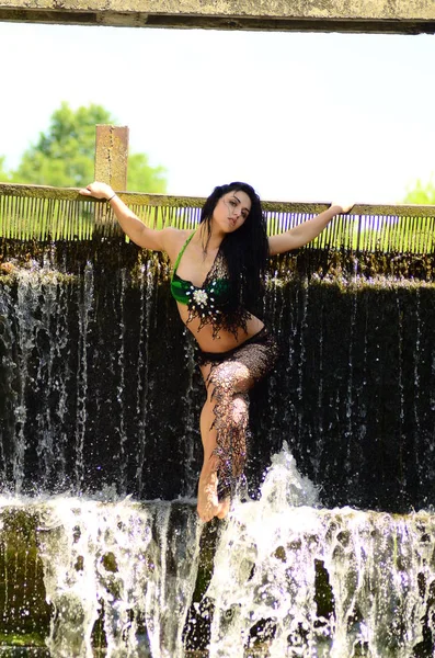 Jeune modèle brune posant contre une cascade — Photo