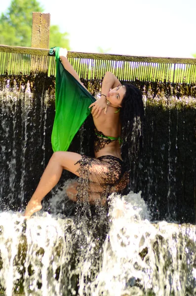 Joven modelo morena posando contra una cascada — Foto de Stock