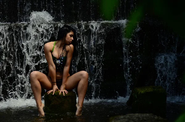 Unga brunett modell poserar mot ett vattenfall — Stockfoto