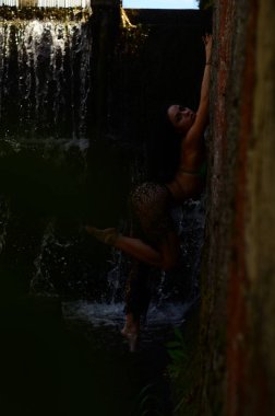 Genç esmer model bir şelale karşı poz