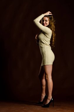 Parlak elbiseli çekici kadın siyah arka planda poz veriyor. 