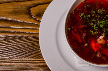 Çorba, ekşi kremalı borç, arka planda boncuk ve turşu. Borç beyaz bir tabakta, ekmek dilimleri ahşap bir kesme tahtasında, turşular ahşap bir tabakta..