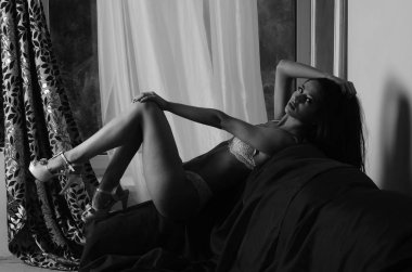 İç çamaşırlarıyla kanepede poz veren sevimli, çekici, çekici bir kızın portresi. 