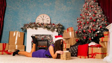 Noel süslemeli stüdyoda şöminenin yanında poz veren çekici esmer kadın.  